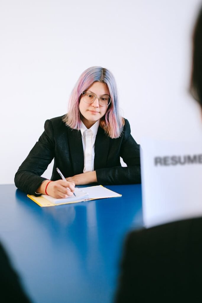 Professional woman with dyed hair taking notes during a job interview.